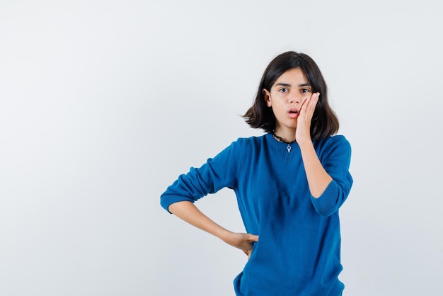 The teenage girl is suprising by putting her hand on cheek on white background