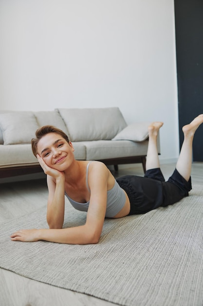 Teenage girl lying on the floor at home smiling in home clothes with a short haircut lifestyle without filters free copy space