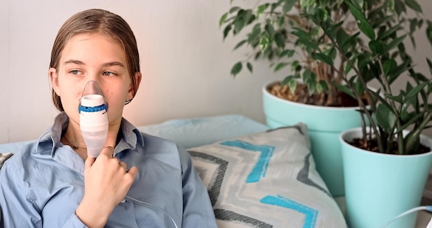 Teenage girl makes inhalation with a nebulizer equipment Sick child holding inhalator in hand and b