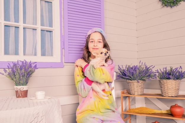 A teenage girl in pajamas and a sleep mask with a chihuahua dog in her arms A girl and a dog