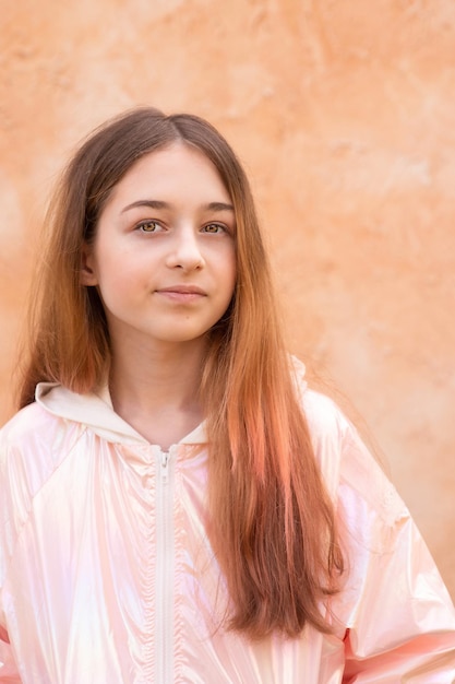 A teenage girl in a pink jacket on a beige background Portrait of a beautiful girl