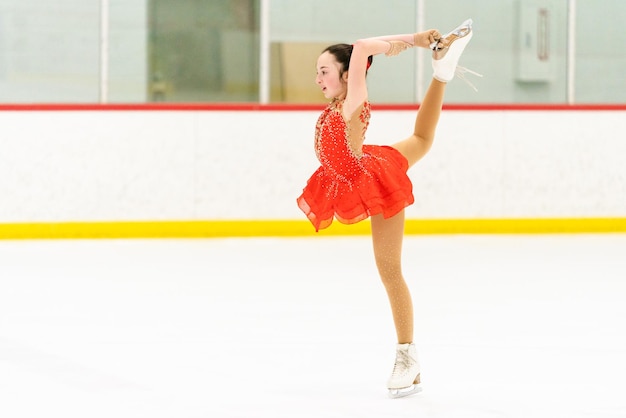 Teenage girl practicing figure skating on an indoor ice skating rink