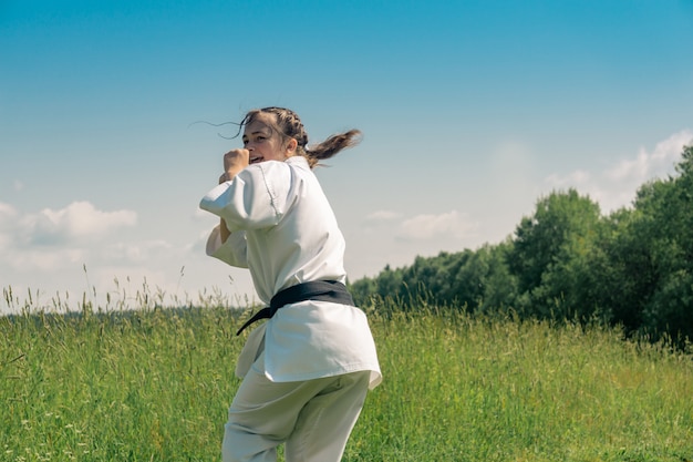 Photo teenage girl practicing karate kata outdoors, prepares to uro mawashi geri (hook kick)