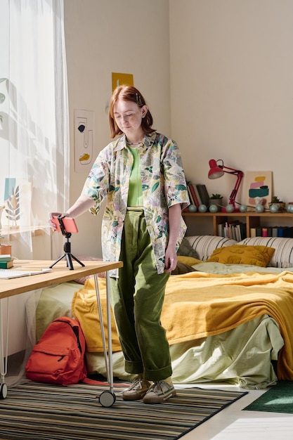 Teenage girl preparing smartphone for online streaming