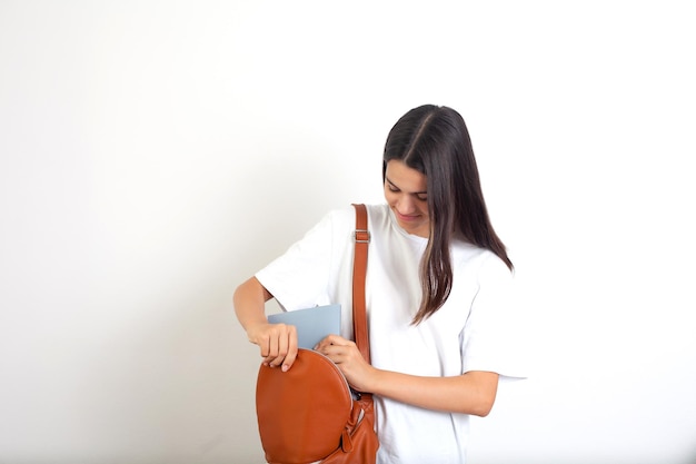 A teenage girl puts notebooks and books in a backpack Schoolgirl student White background Study A place for text