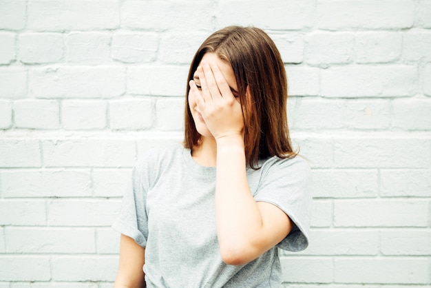 Teenage girl shows facepalm gesture on the street.