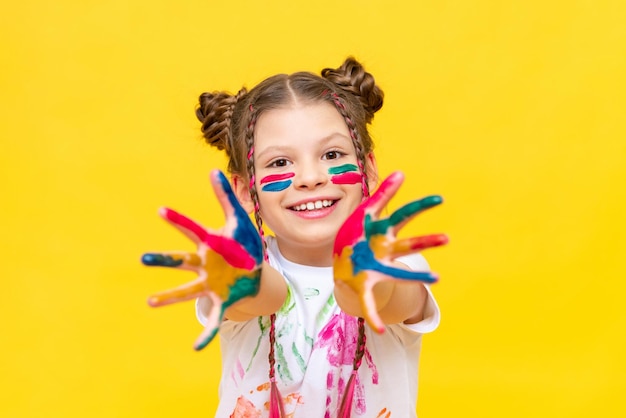 A teenage girl smeared with multicolored paint shows her palms and smiles broadly The art of drawing for schoolchildren Courses in freehand drawing Colors of life