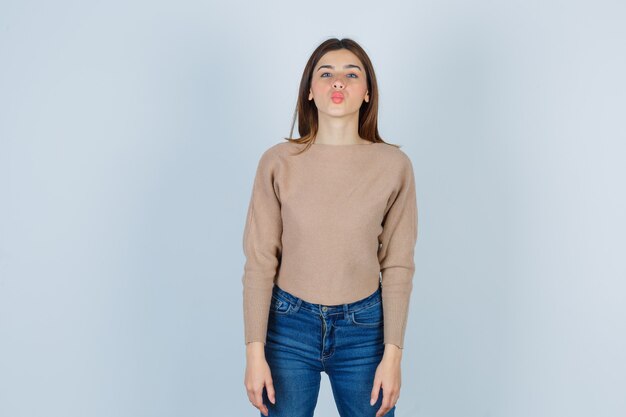 Teenage girl in sweater, jeans pouting lips and looking alluring , front view.