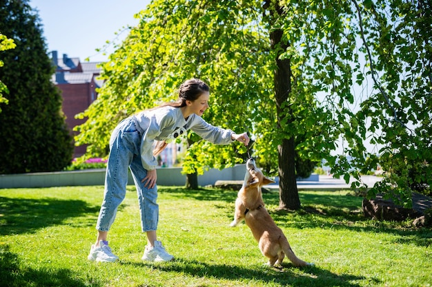 Teenage girl teasing her little dog while playing with it