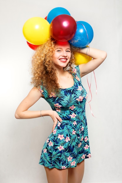 teenage girl with helium balloons over gray background