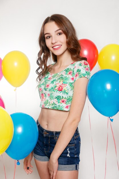 teenage girl with helium balloons over gray background