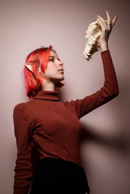 Teenage girl with pink hair and a dog skull in her hands