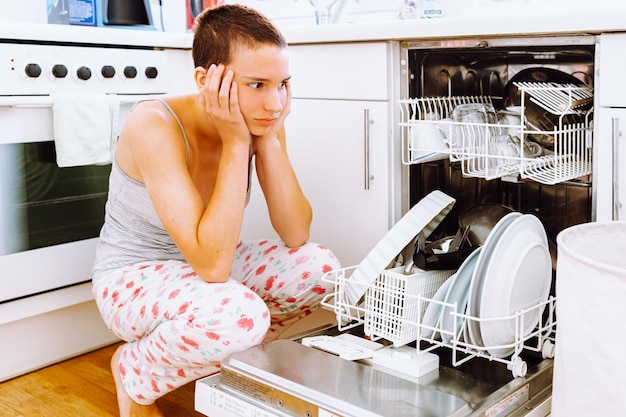 teenage girl with short hair, in home clothes, clutched head from fatigue from home routine.