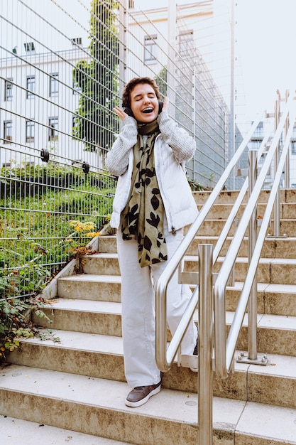 teenage girl with short haircut, in warm white jacket, listens to music on headphones