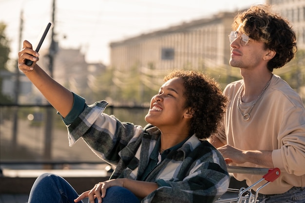 Teenage girl with smartphone making selfie with her boyfriend