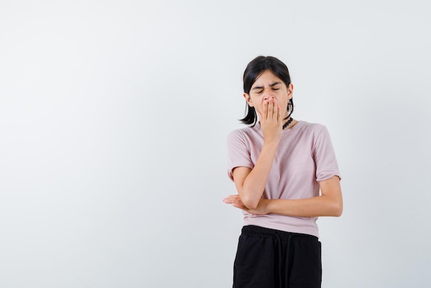 Teenage girl yawning on white background