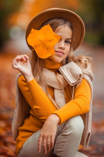 a teenage girl in a yellow sweater walks along a street outside the city against the backdrop of yellow trees fun walk in autumn