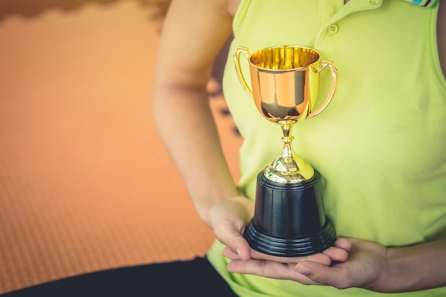 Teenage girls' hands are holding trophies congratulations on success.