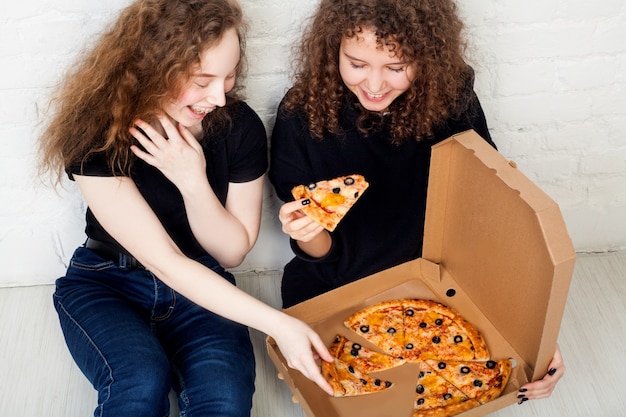 Teenage girls holding a box of pizza and smiling. concept of pizza delivery.