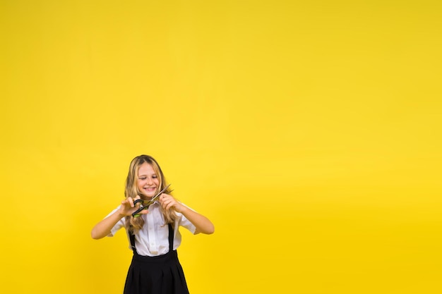 Teenage school girl with scissors isolated on yellow background Child creativity arts and crafts