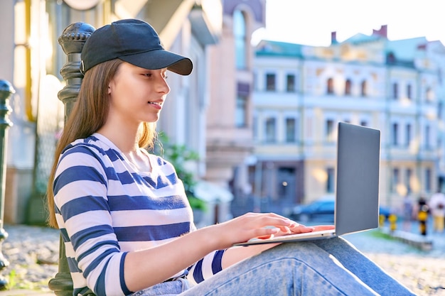 Teenage student girl using laptop outdoor urban background