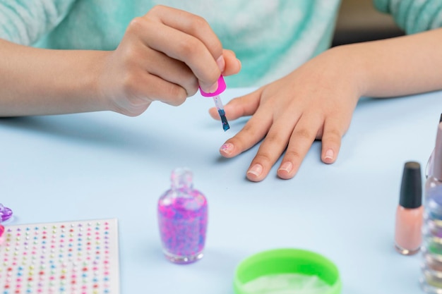 Teenage woman painting her nails at home with nail supplies on the table