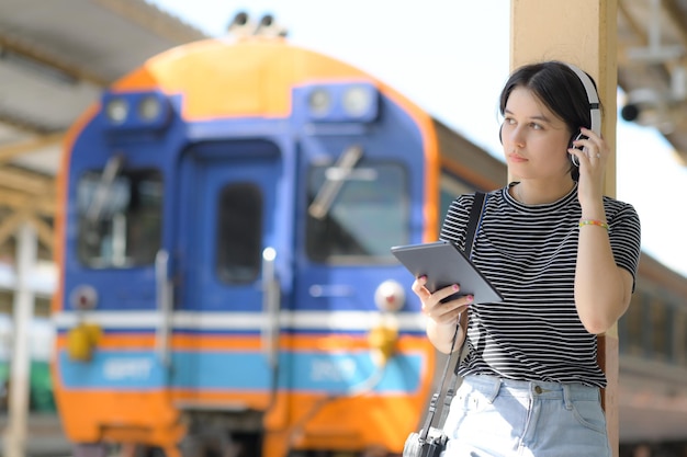 A teenage woman wearing headphones listening to music from an app on a tablet