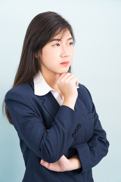 Teenage young girl wearing suit with hand on chin isolated on blue background