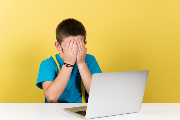 Teenager boy hands on face in front of laptop