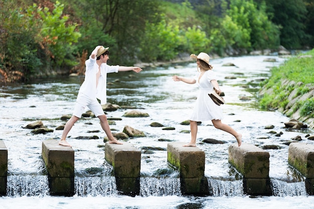 Teenager boy helping girl to cross river