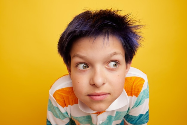 Teenager boy looks away in surprise on isolated on light yellow background