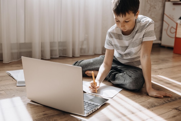 Teenager boy lying on floor with laptop having video call and online lesson at home Schoolboy studying homework Distance education remote training concept