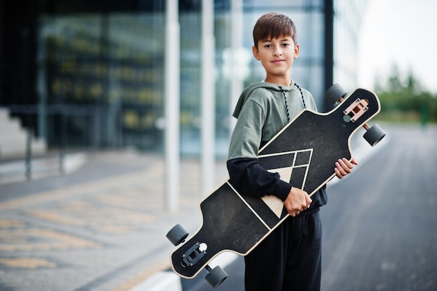 Teenager boy in a sports suit with longboard