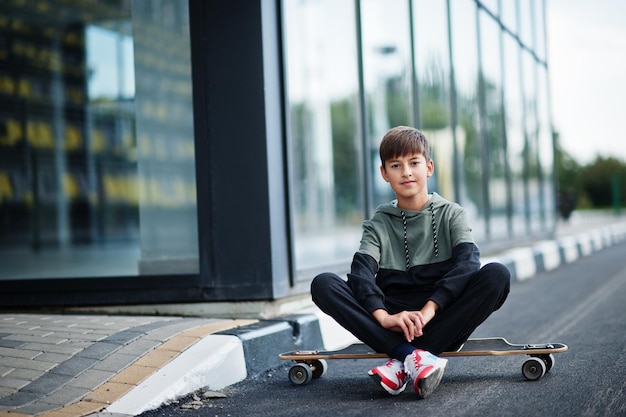 Teenager boy in a sports suit with longboard