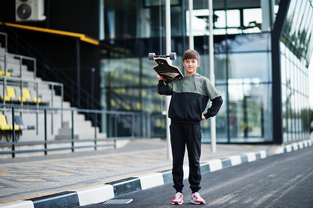 Teenager boy in a sports suit with longboard