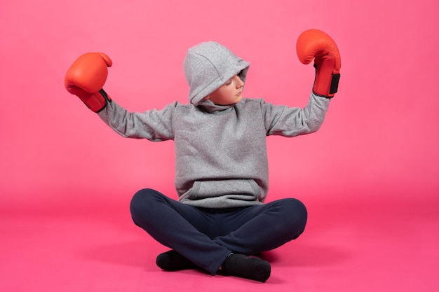 Teenager boy wearing boxing gloves looking at biceps