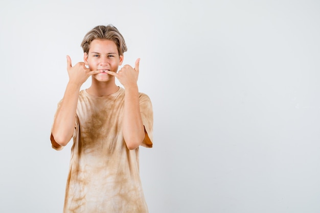 Teenager boy whistling with fingers in t-shirt and looking cool , front view.