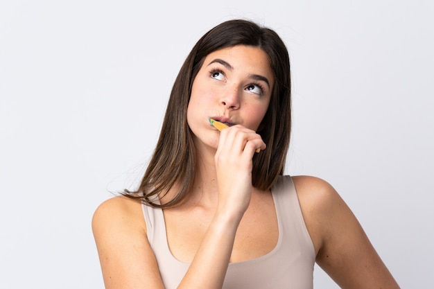 Teenager Brazilian girl brushing her teeth over isolated white wall