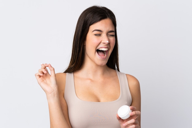 Teenager Brazilian girl with moisturizer over isolated white wall