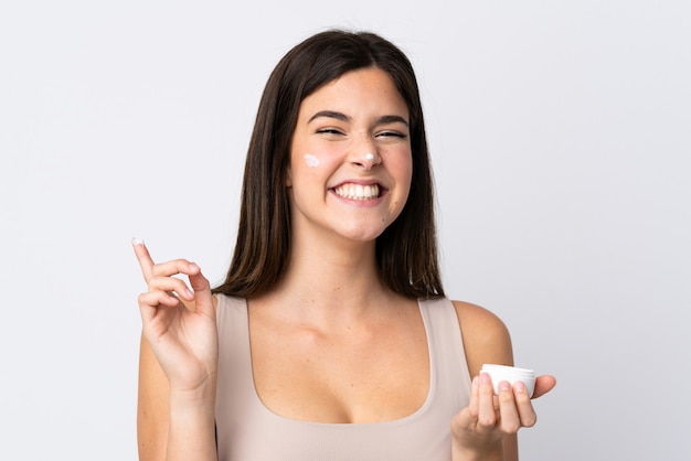 Teenager Brazilian girl with moisturizer over isolated white wall