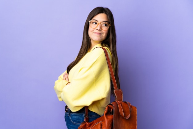 Teenager Brazilian student girl over isolated purple wall laughing