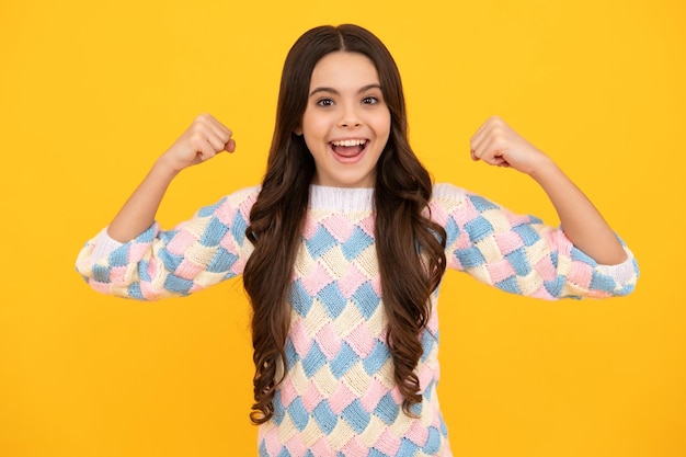 Teenager child girl rejoicing say yes looking happy and celebrating victory champion gesture fist pump on yellow background Excited face Amazed expression cheerful and glad