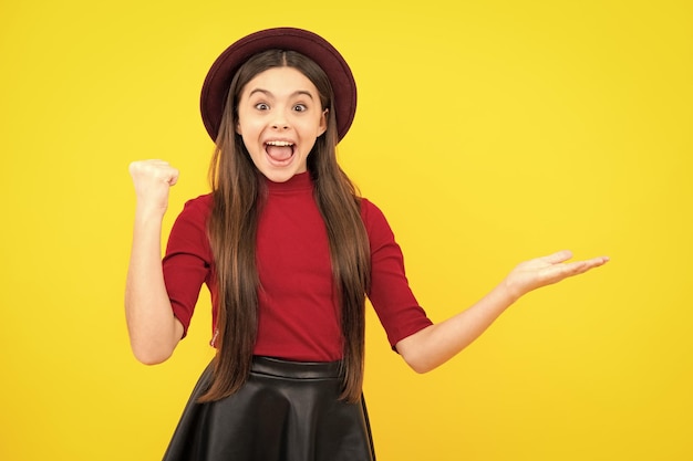 Teenager child pointing to the side with a finger to present a product or idea Teen girl in casual outfit pointing empty space Excited teenager glad amazed and overjoyed emotions