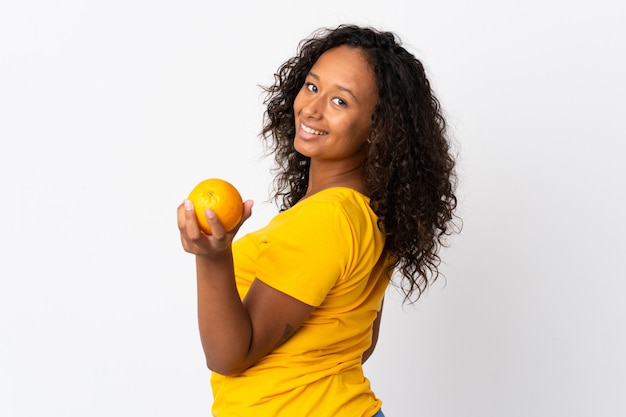 Teenager cuban girl isolated on white  holding an orange