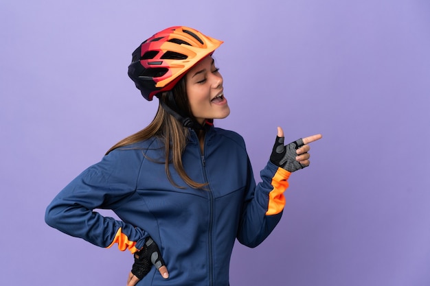 Teenager cyclist girl pointing finger to the side and presenting a product