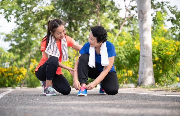 Teenager daughter take care Asian older mother with exercise walking at park