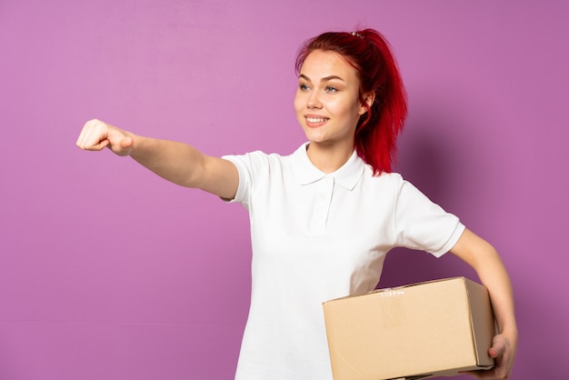 Teenager delivery girl isolated on purple background giving a thumbs up gesture