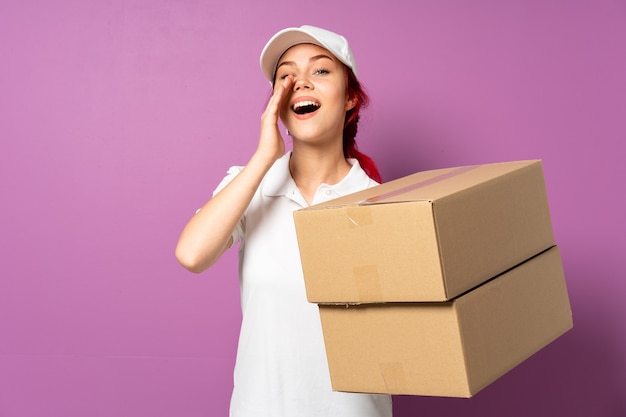 Teenager delivery girl isolated on purple background shouting and announcing something