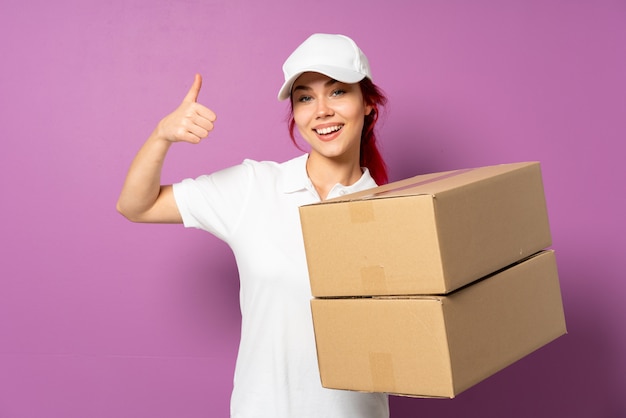 Teenager delivery girl on purple wall giving a thumbs up gesture