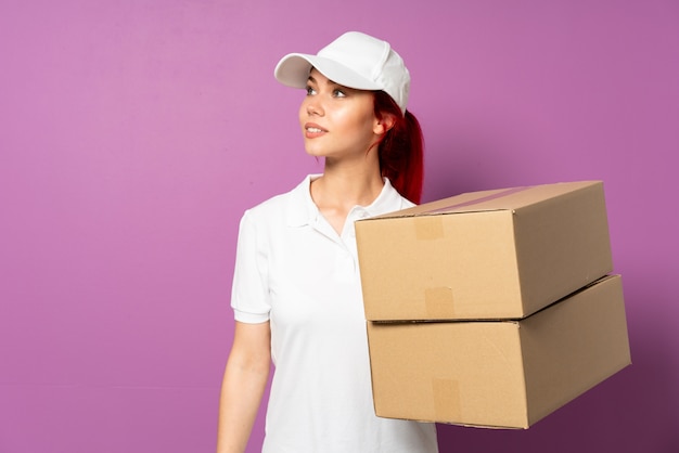 Teenager delivery girl on purple wall looking to the side